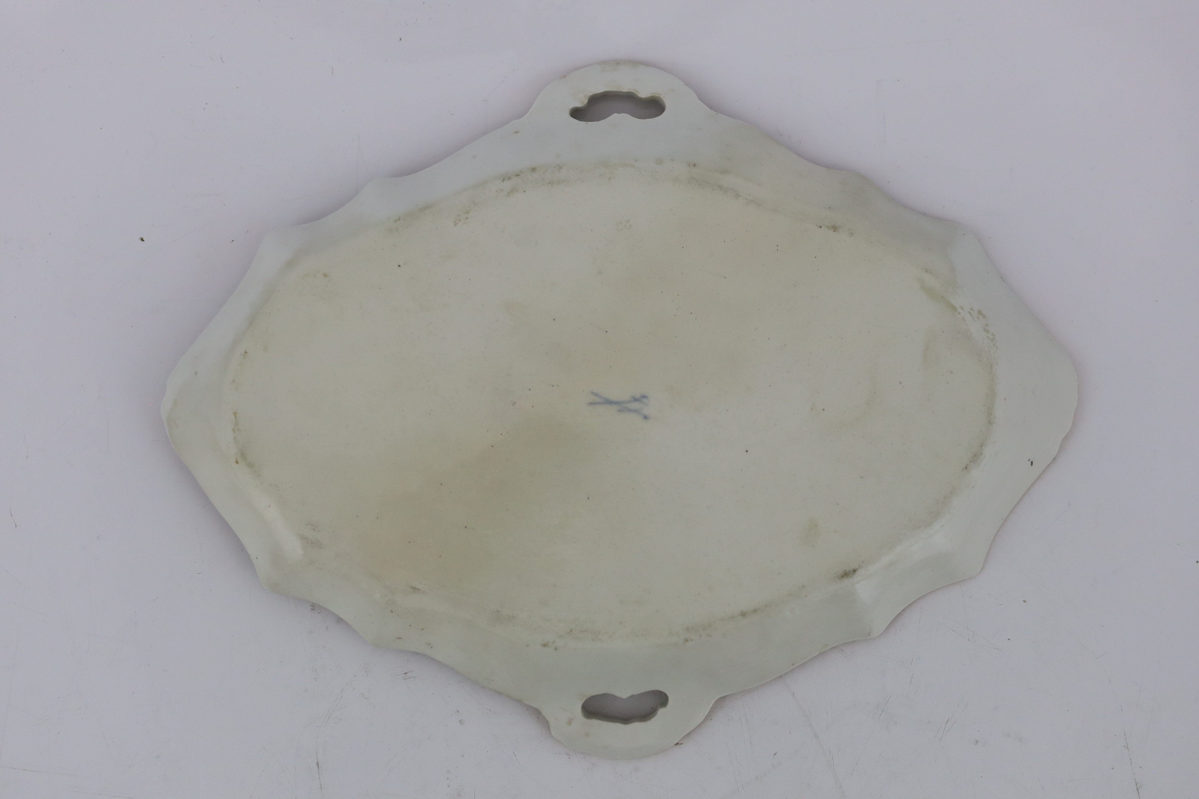 A Meissen porcelain lozenge shaped tray, 19th century, painted with figures in seascapes, ozier moulded ground, underglaze blue crossed swords mark and incised model number 712, 37.7cm wide, broken and restored